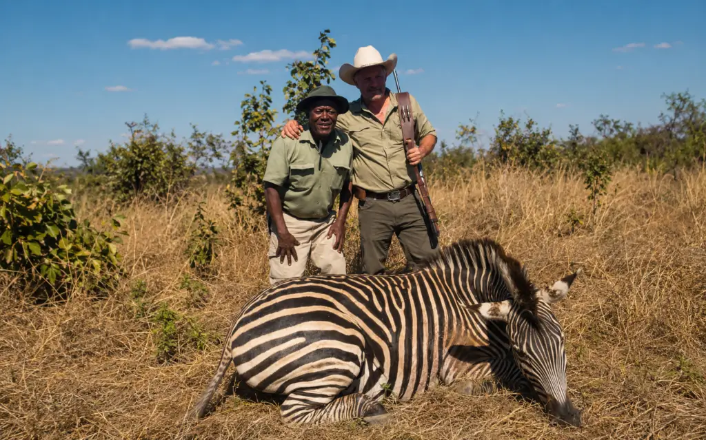 Hunter and professional guide posing with a zebra trophy in the Zimbabwean bush
